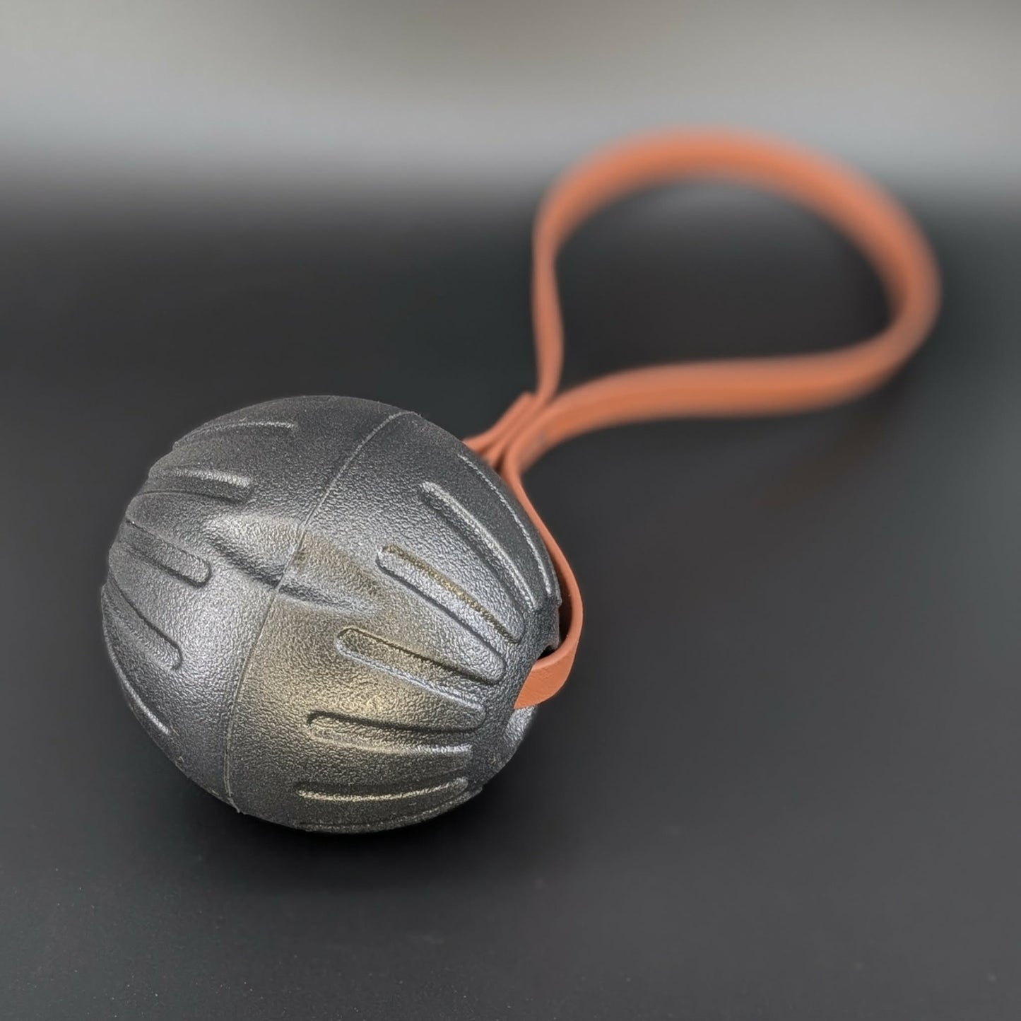 large black eva foam ball tug with a brown biothane loop handle