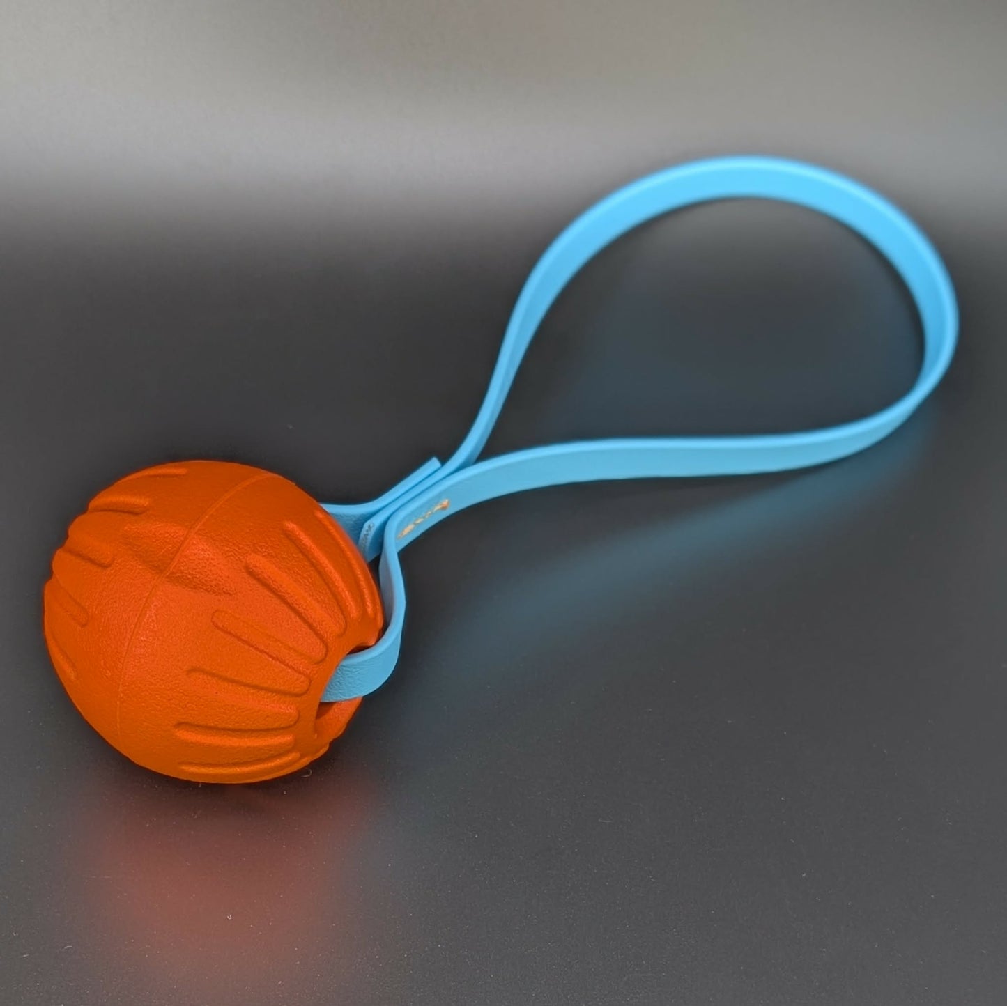 medium orange eva foam ball tug with a light blue biothane loop handle