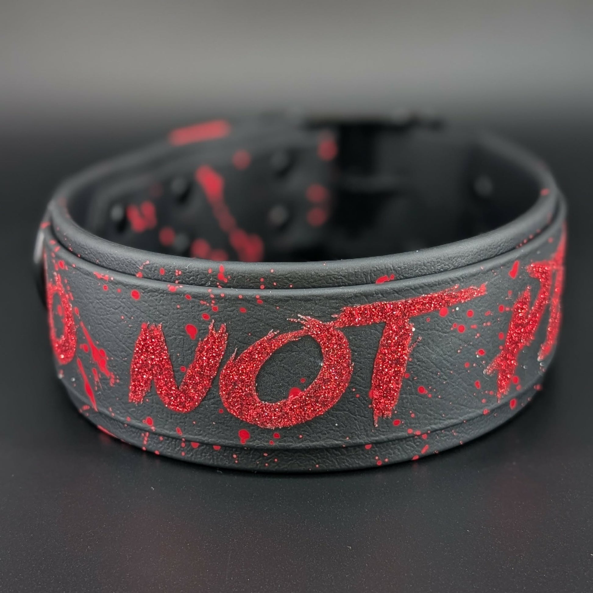 2 inch wide black layered biothane dog collar with black hardware and red glitter do not pet text and splatter paint