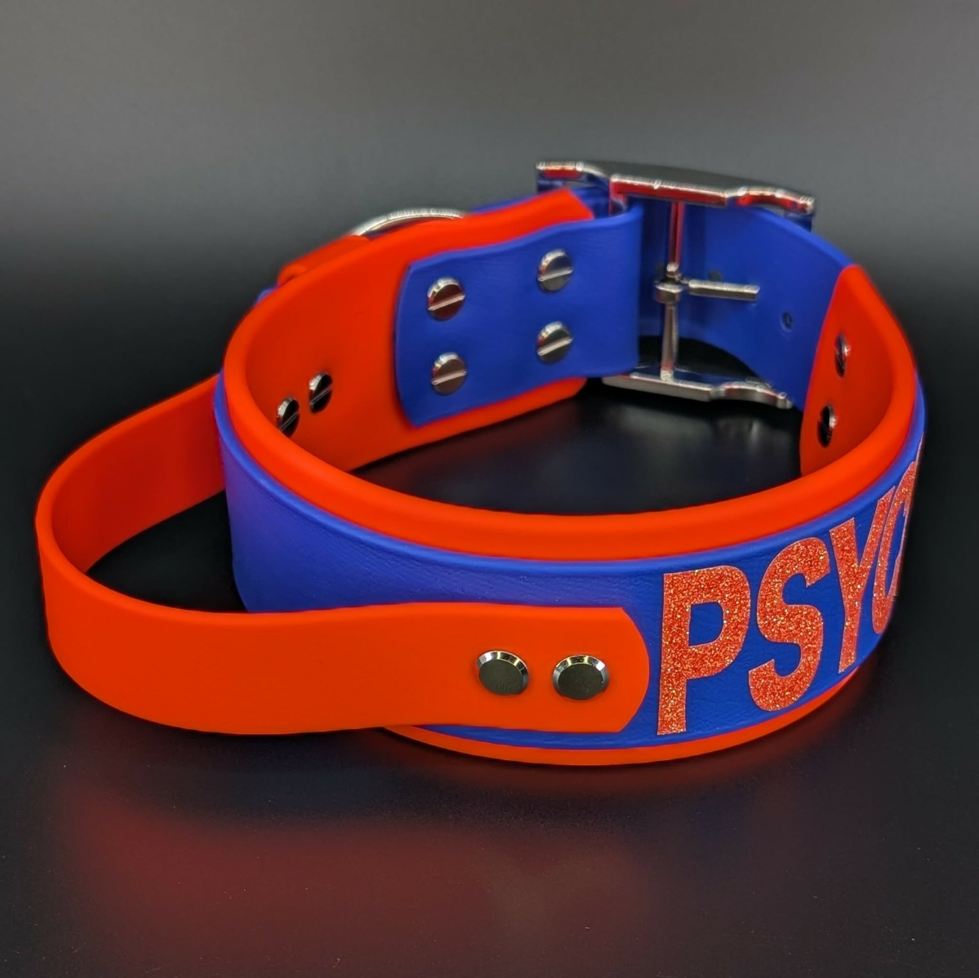2 inch wide orange and royal blue layered biothane dog collar with tactical handle and psycho glitter text