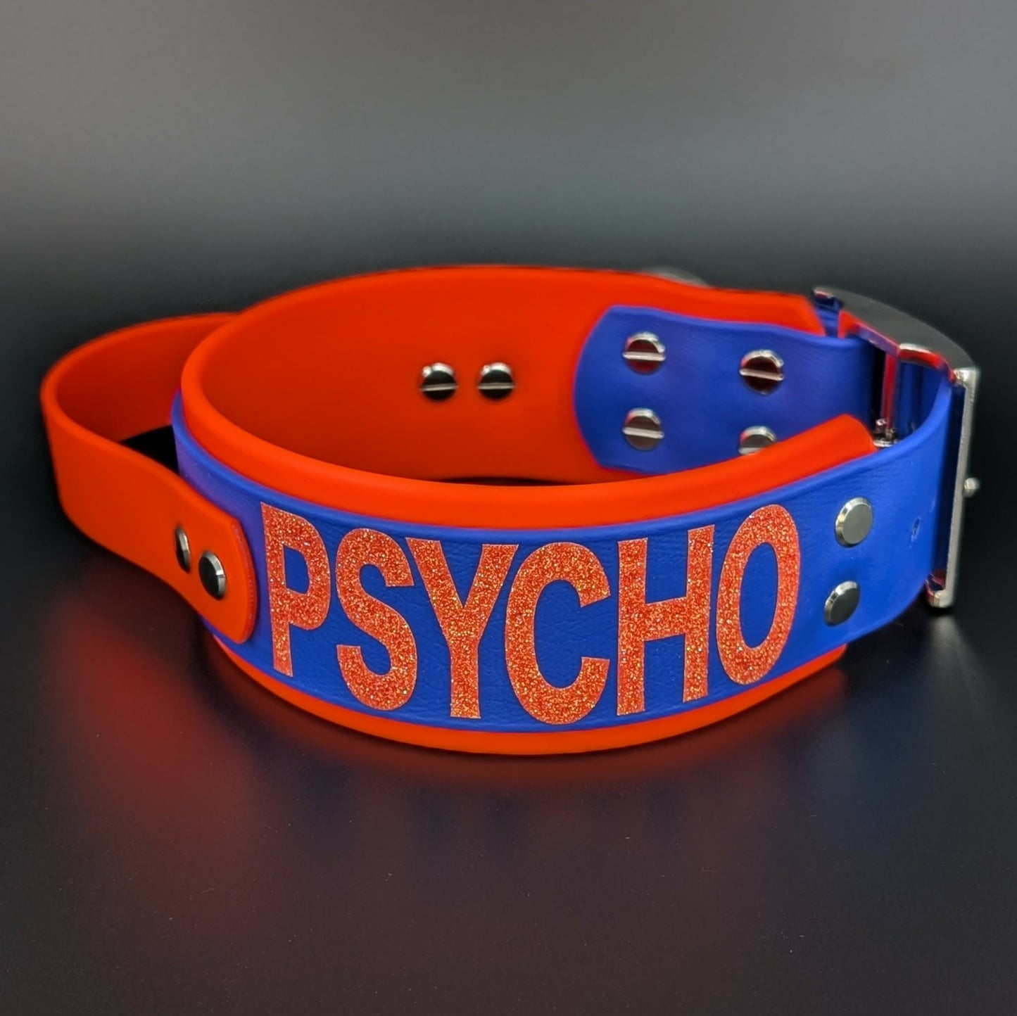 2 inch wide orange and royal blue layered biothane dog collar with tactical handle psycho glitter text
