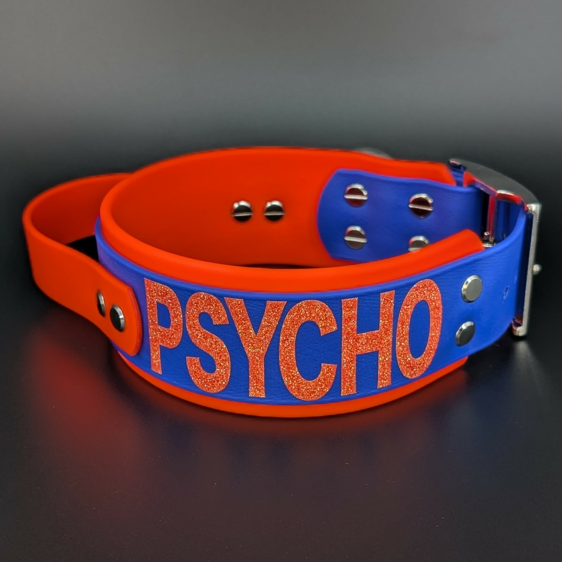 2 inch wide orange and royal blue layered biothane dog collar with tactical handle psycho glitter text