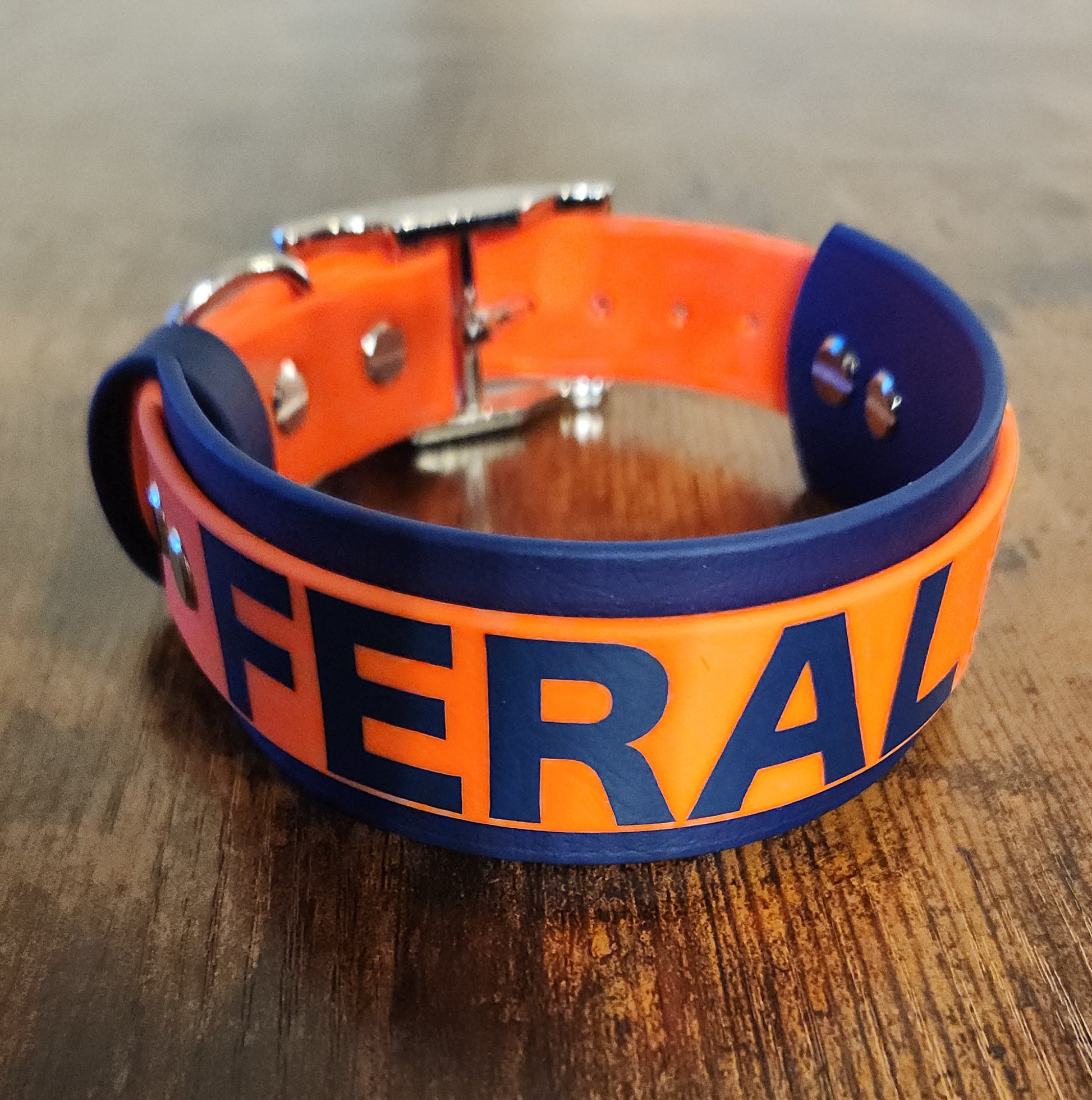 dark blue and orange layered biothane dog collar reading "FERAL"