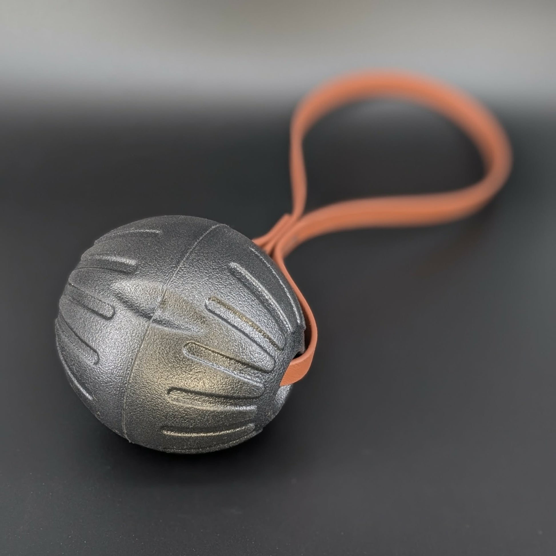 large black eva foam ball tug with a brown biothane loop handle