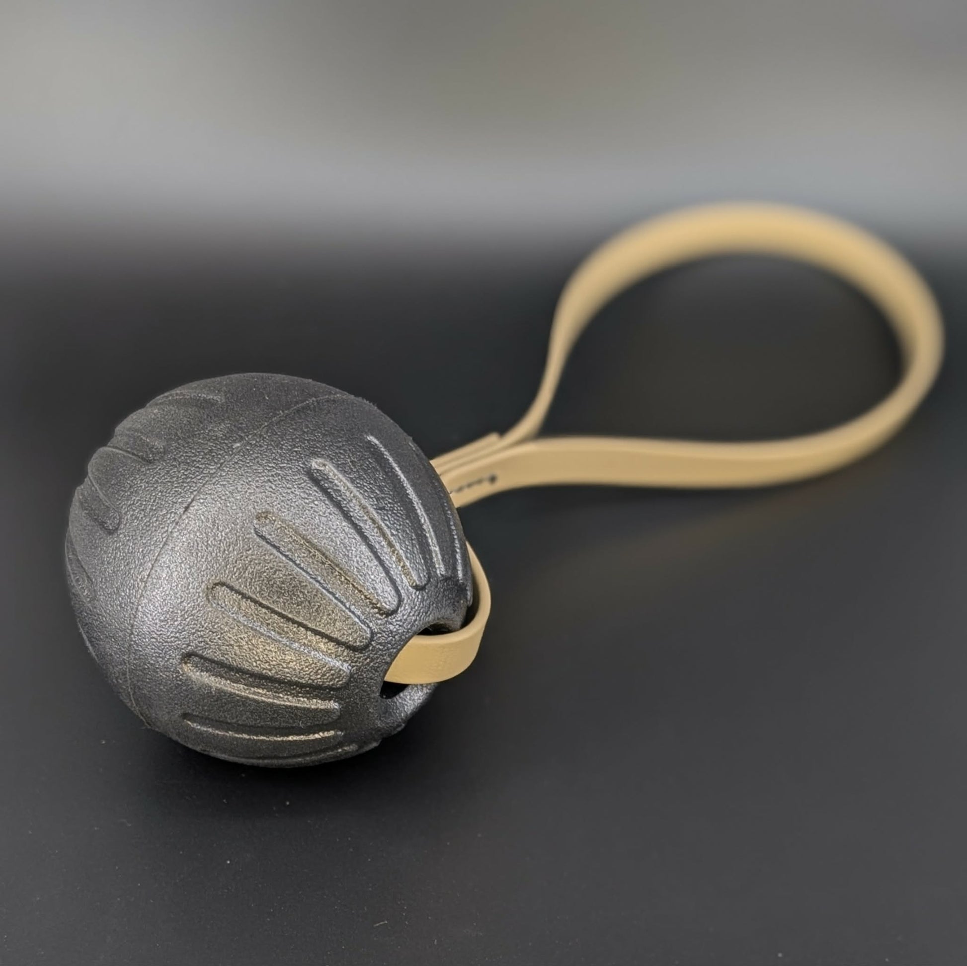 large black eva foam ball tug with a tan biothane loop handle
