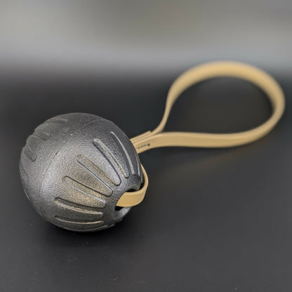 large black eva foam ball tug with a tan biothane loop handle