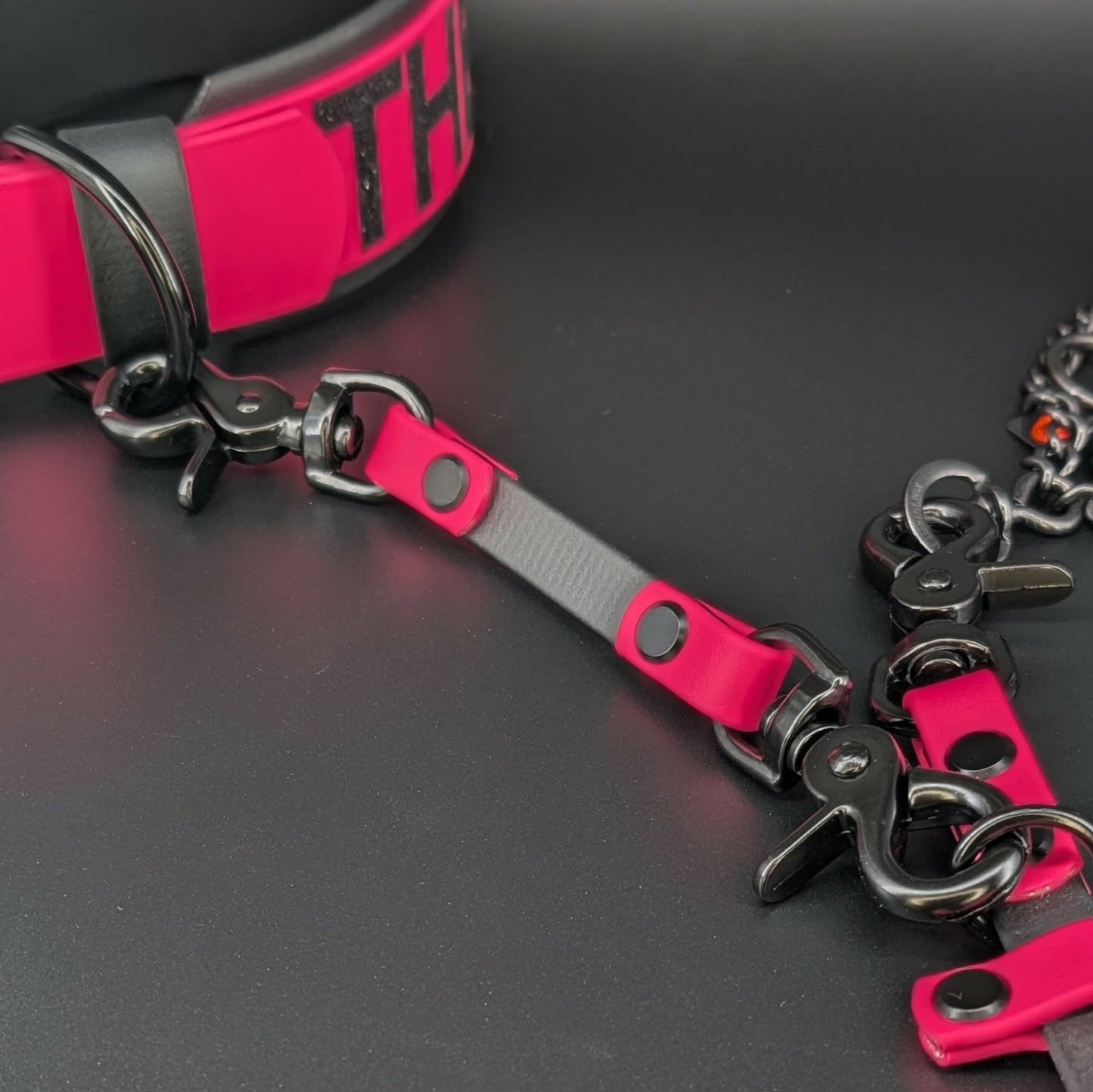 pink and black biothane prong collar safety backup clip attached to prong and backup collar 