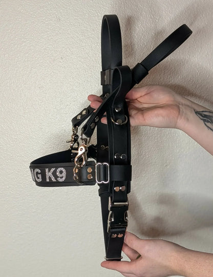 ready to ship layered black biothane straight front service dog harness with counterbalance handle and pull strap and working k9 text across the chest strap